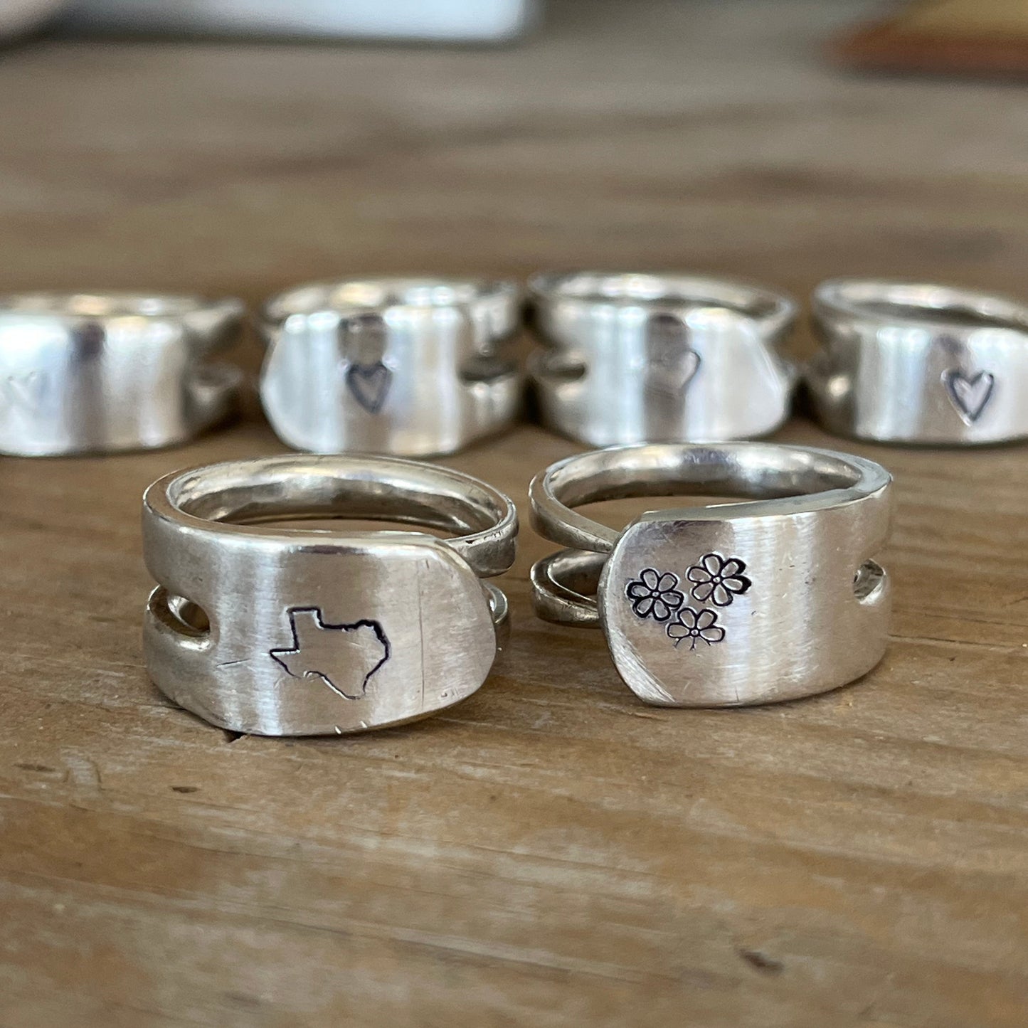 Group of hand stamped double fork tine rings of various designs - texas, daisies and hearts