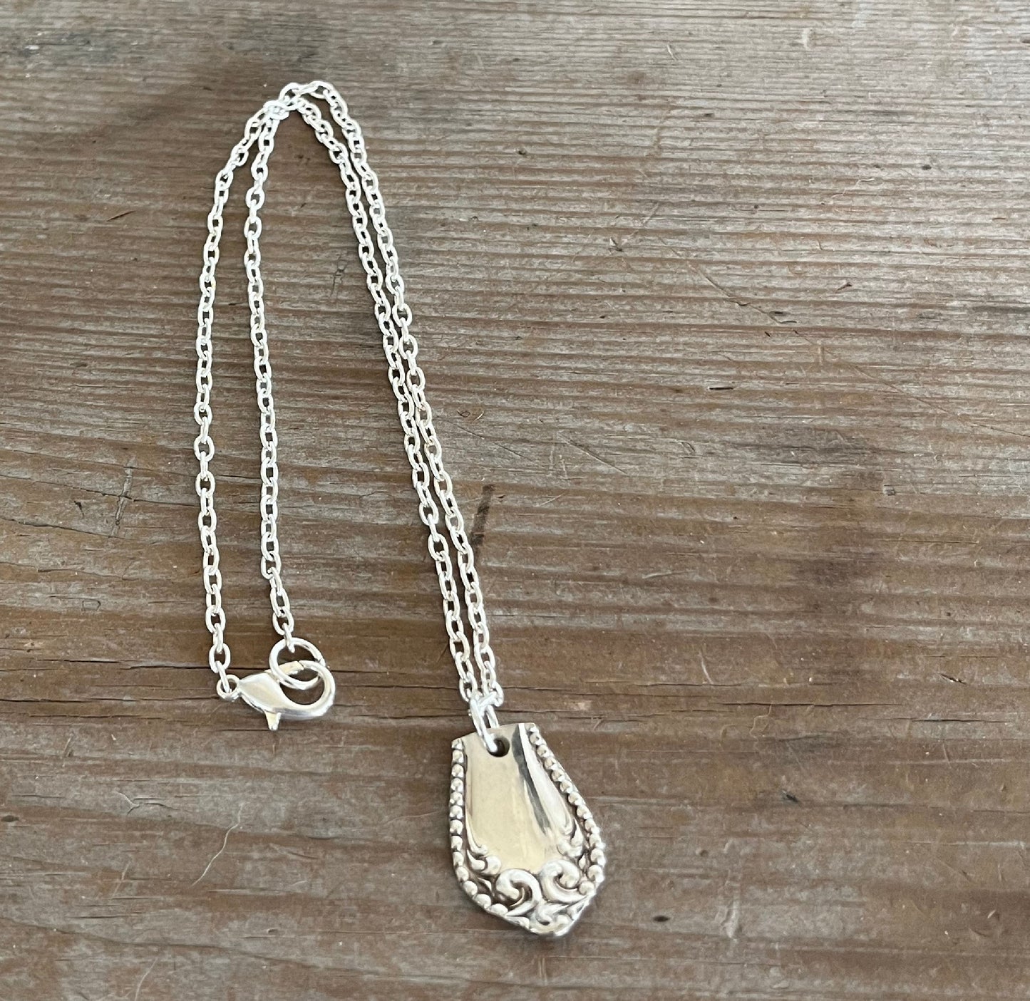 Close-up of Pearl Fenwick silverplate spoon pendant showing dots and swooshes pattern detail, handpolished vintage silverware necklace