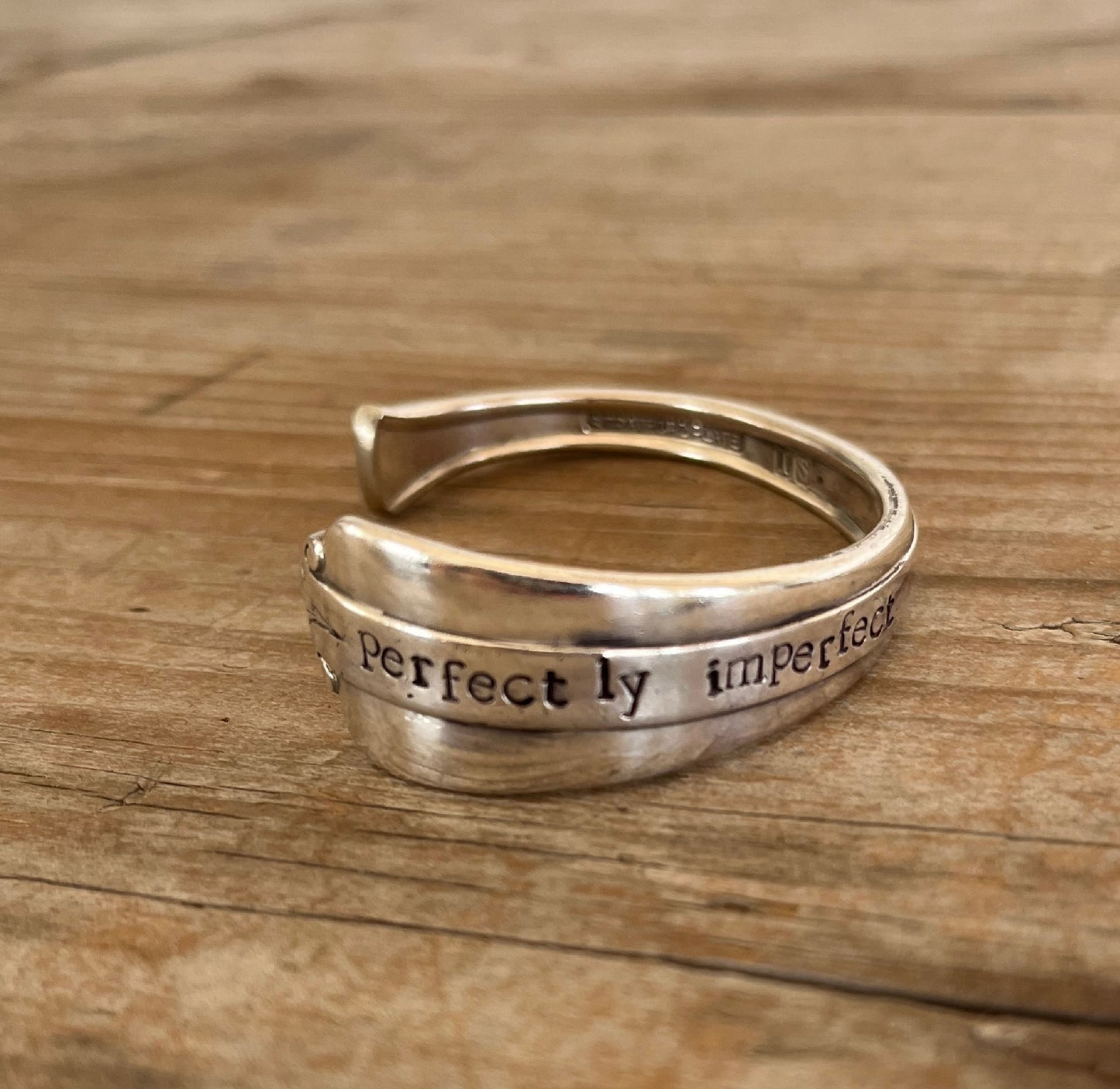 Close-up flat lay of PERFECTLY IMPERFECT hand-stamped spoon cuff bracelet - upcycled vintage Stratford Silverplate Starlight pattern - Laughing Frog Studio