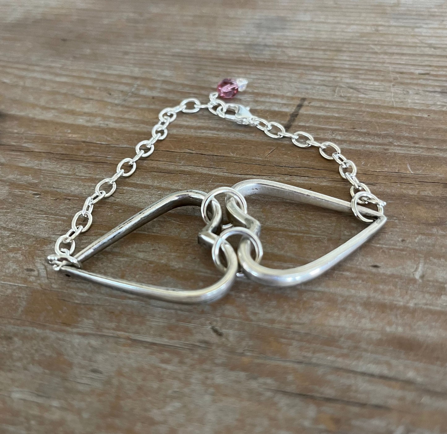 Close-up detail of fork tine heart charm on relationship bracelet - handcrafted upcycled silverware artisan jewelry