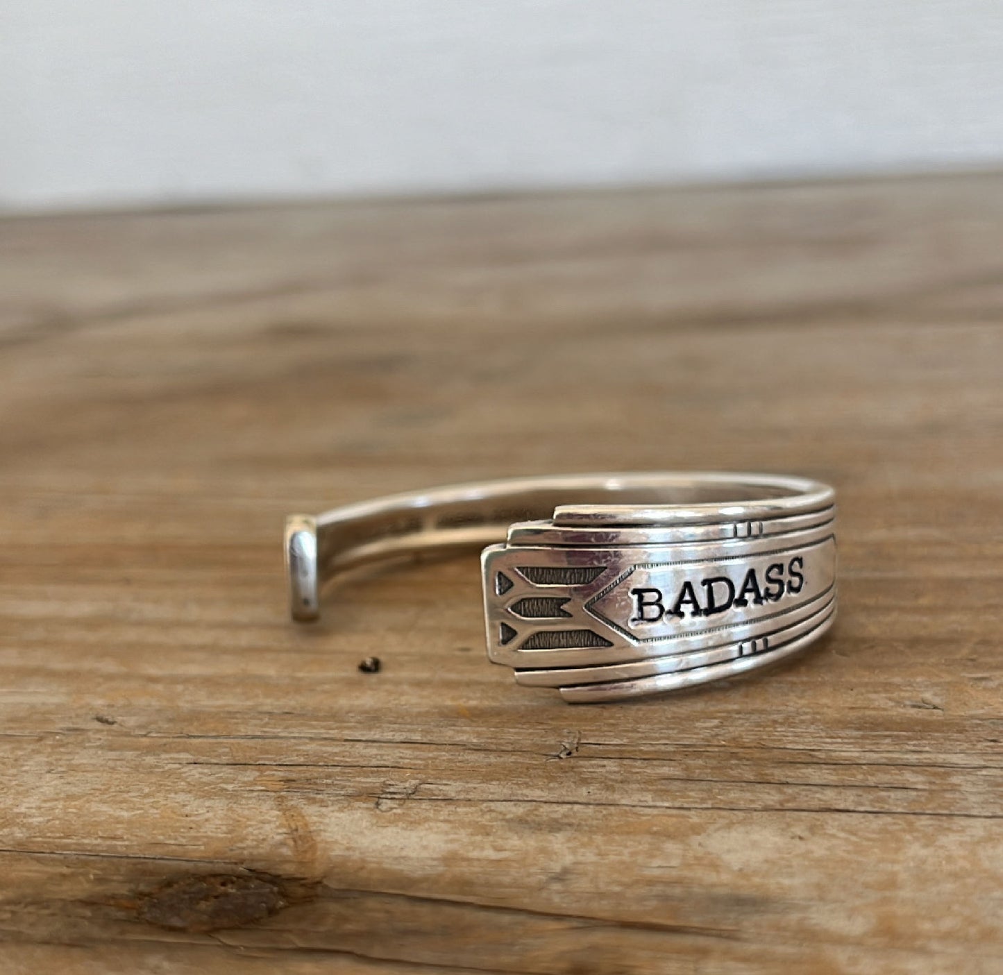 Close-up detail of BADASS hand-stamped spoon cuff bracelet showing Friendship/Medality pattern and vintage silverplate