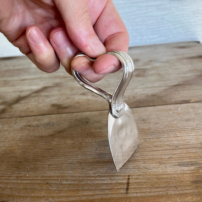 Close-up of ergonomic heart-shaped handle with finger indents on Cheshire spoon cheese knife