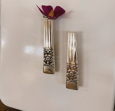 Upcycled vintage 1936 Community Coronation silverplate knife vase with magnet holding single flower on metal surface