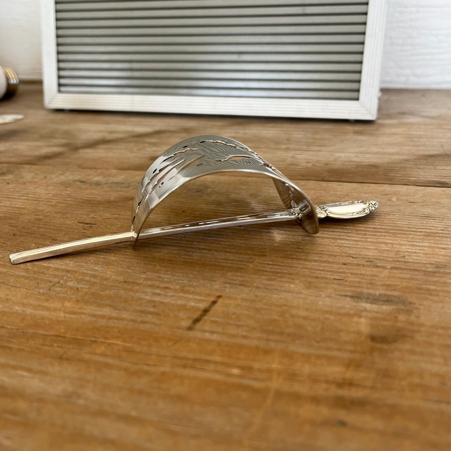 Profile view of handmade cake server barrette showing curved vintage silverplate shape