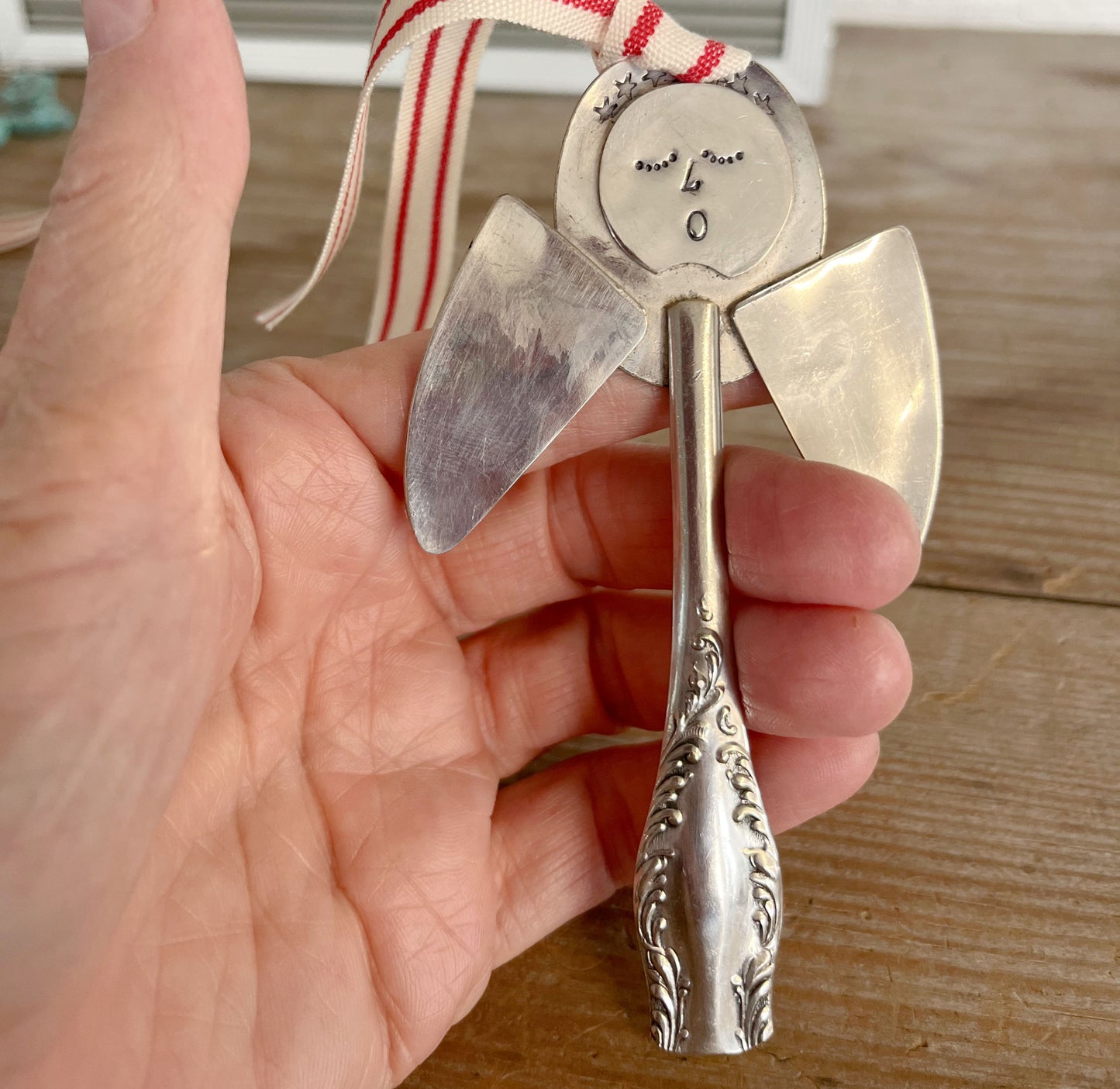 Pearl artisan angel ornament with spoon handle body and spoon bowl wings with red striped ribbon hanger shown in hand for scale - handcrafted upcycled vintage silverware ornament - Laughing Frog Studio