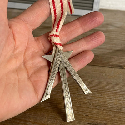 Scrap silverware Christmas tree shaped ornament with a star and red striped ribbon hanger shown in hand for scale - handcrafted upcycled vintage silverware ornament - Laughing Frog Studio