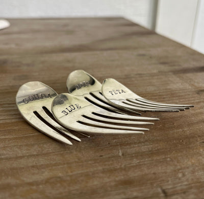 Hand-stamped vintage fork cheese markers detail - convex curved antique silverware with bold uppercase font