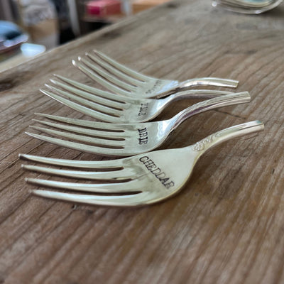 Hand-stamped vintage fork cheese markers detail - convex curved antique silverware with bold uppercase font