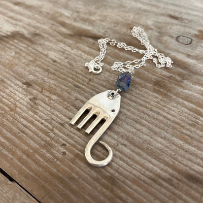 Close-up detail of handcrafted fork elephant pendant with smoky blue bead, 1.75 inches tall
