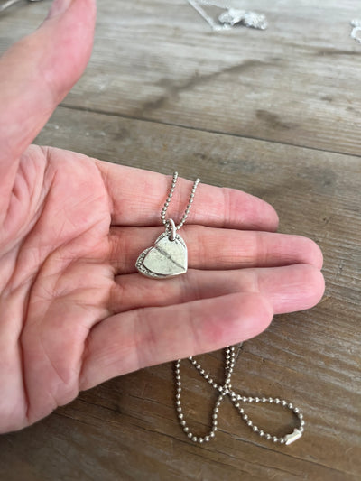 Close-up of Mary Lou fork tine heart pendant showing delicate floral pattern detail on vintage silverplate necklace - shown in hand for scale