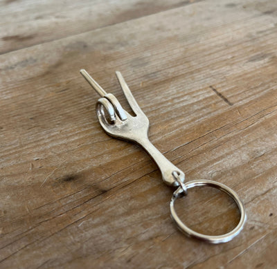 Profile view of vintage fork keychain peace sign showing dimensional hand gesture and silverware texture