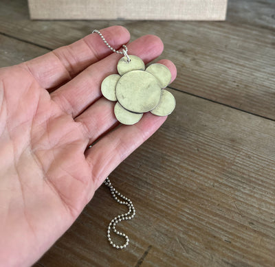 Close-up of 1970s-inspired daisy flower pendant made from repurposed silverplate spoons