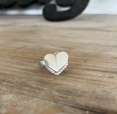 Close-up of heart-shaped spoon ring showing dual vintage silverplate handles joined to form heart design