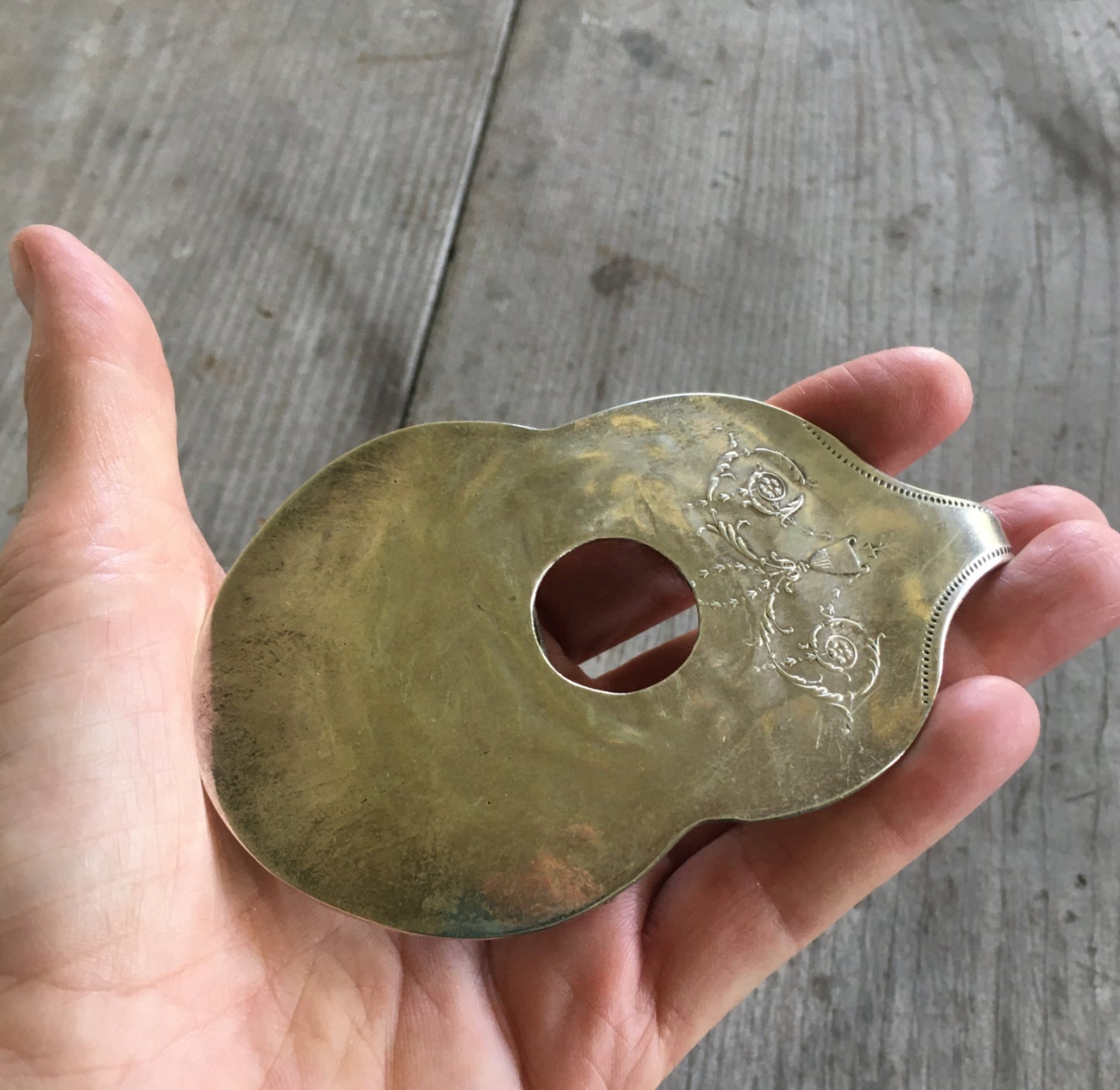 Guitar belt buckle held in hand for scale showing vintage Community Silverplate guitar shape with sound hole, handcrafted music lover accessory