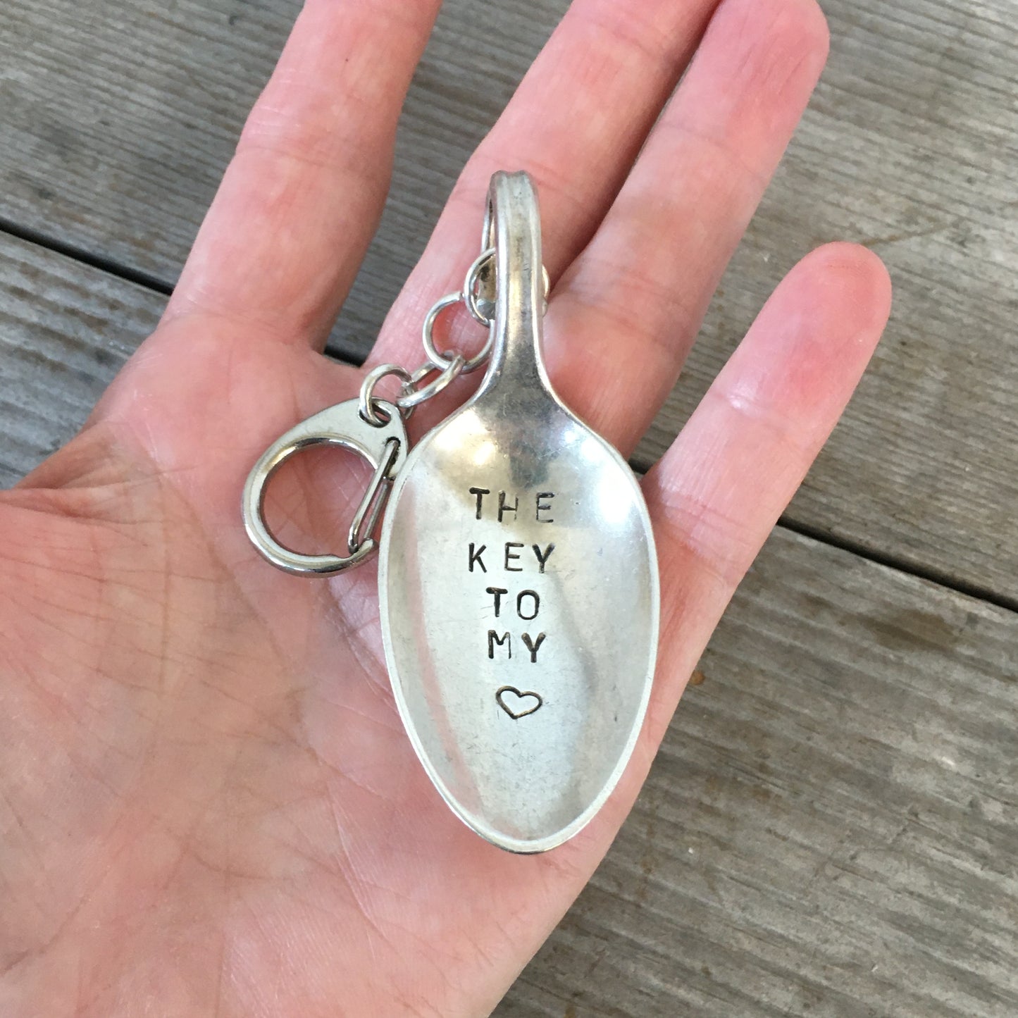 The Key to My Heart Hand Stamped Spoon Keychain shown in hand for scale