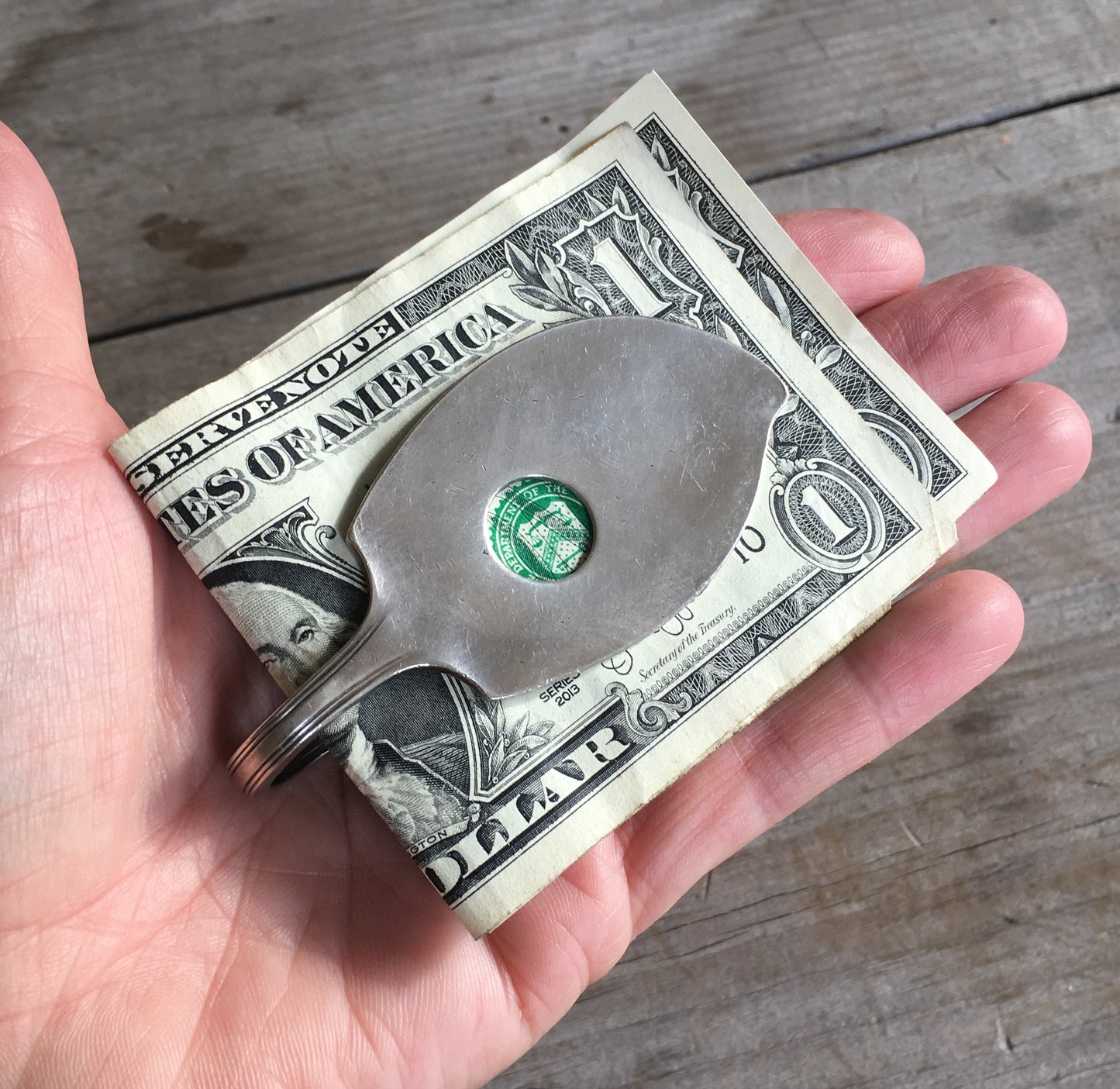 Handmade money clip shown in hand for scale shaped like a guitar or ukele