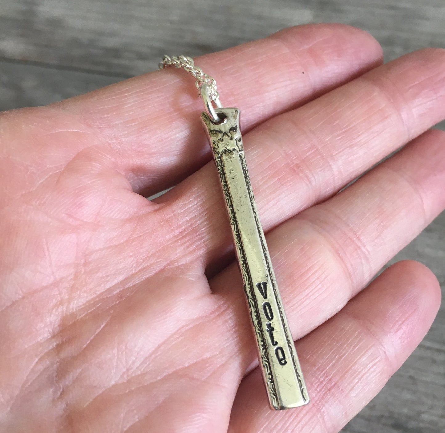 Upcycled silverware Necklace Hand Stamped Vote shown in hand for scale