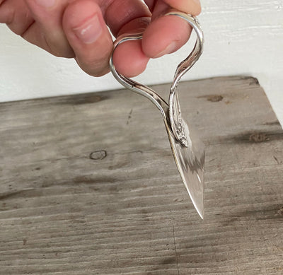 Side view of exclusive handle design on Front Angle view of ergonomic cheese knife made from an upcycled vintage spoon