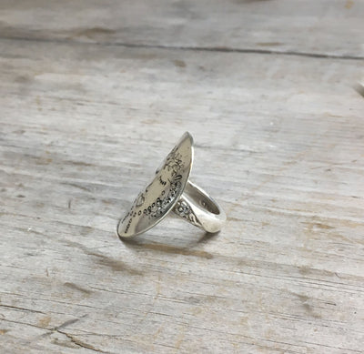 Close-up of nature-inspired Willow spoon ring showing hand-stamped symbols and flower stem shank detail