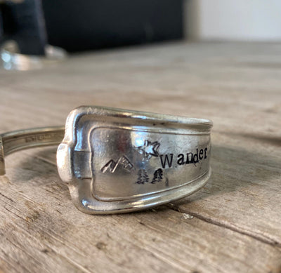 Close-up detail of WANDER hand-stamped spoon cuff bracelet showing mountain and evergreen design with vintage hotel silverplate