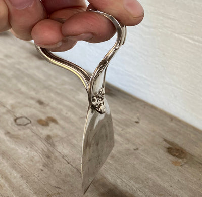 Sterling charcuterie knife with heart handle construction shown in hand for ergonomic design