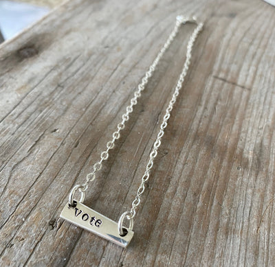 Close-up detail of VOTE bar choker showing hand-stamped lettering on vintage silverware, sits at collarbone, 6.5-inch drop