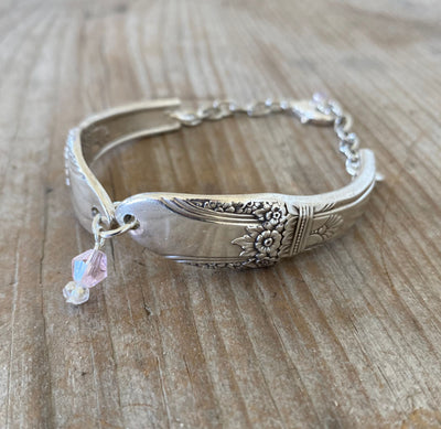 Close-up of handmade FIRST LOVE spoon links showing detailed vintage silverware pattern