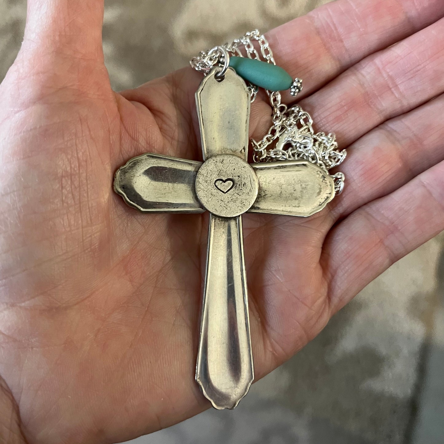 Spoon Necklace with Cross Pendant with Heart on Back Shown in Hand for scale