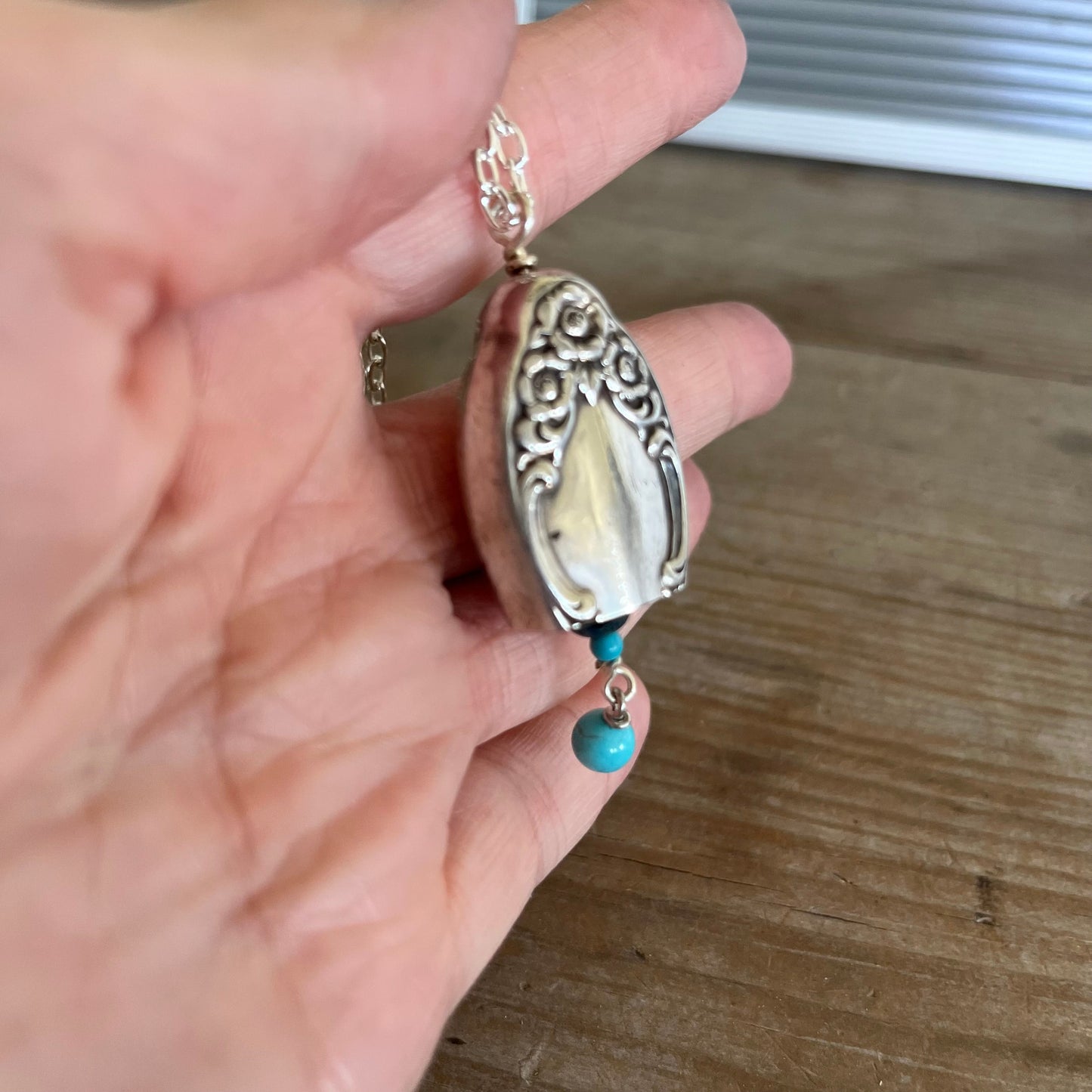Side view of sustainable silverware jewelry bell necklace on chain, handmade from vintage 1958 knife handle