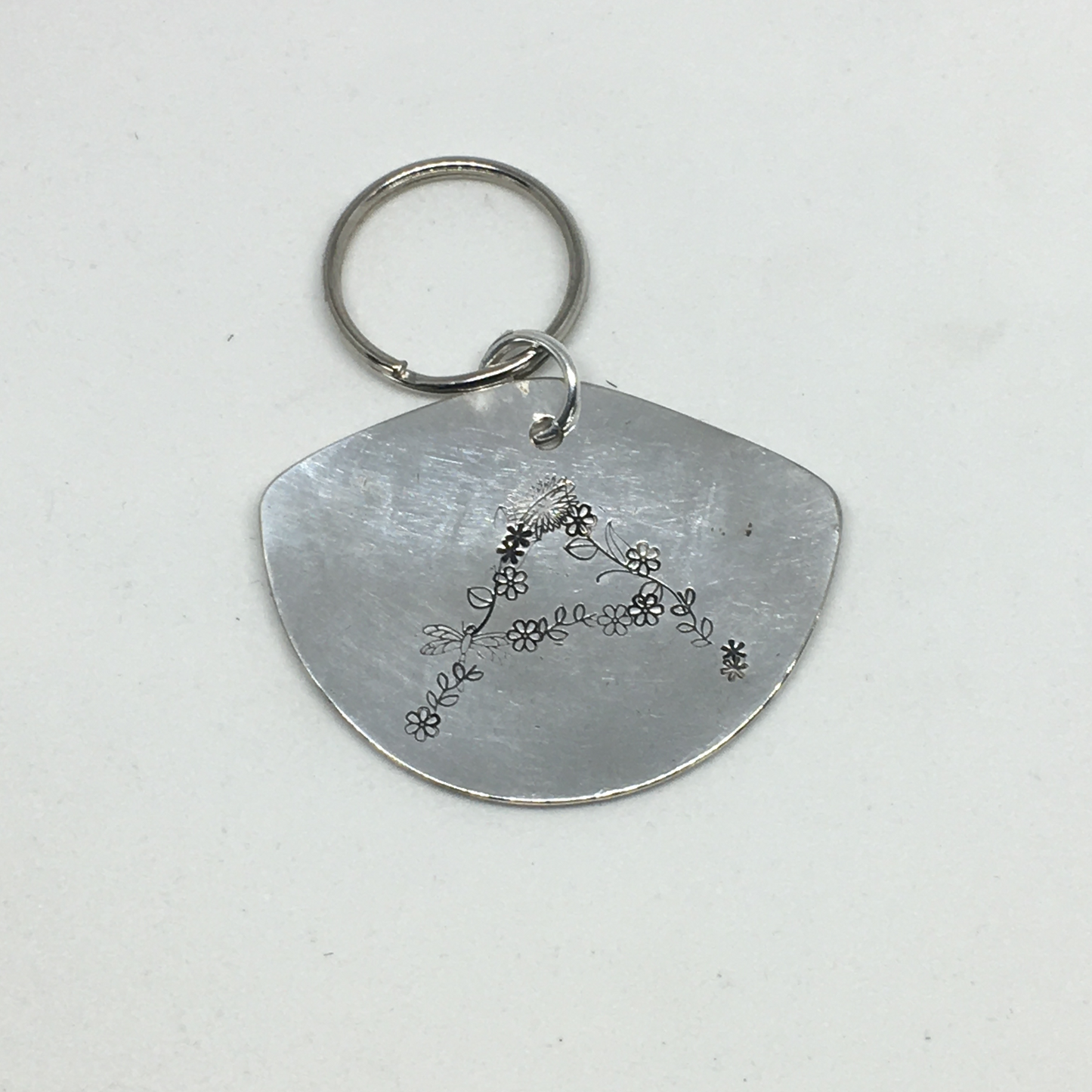 Close-up of floral monogram A hand-stamped on vintage spoon keychain showing spring flower detail