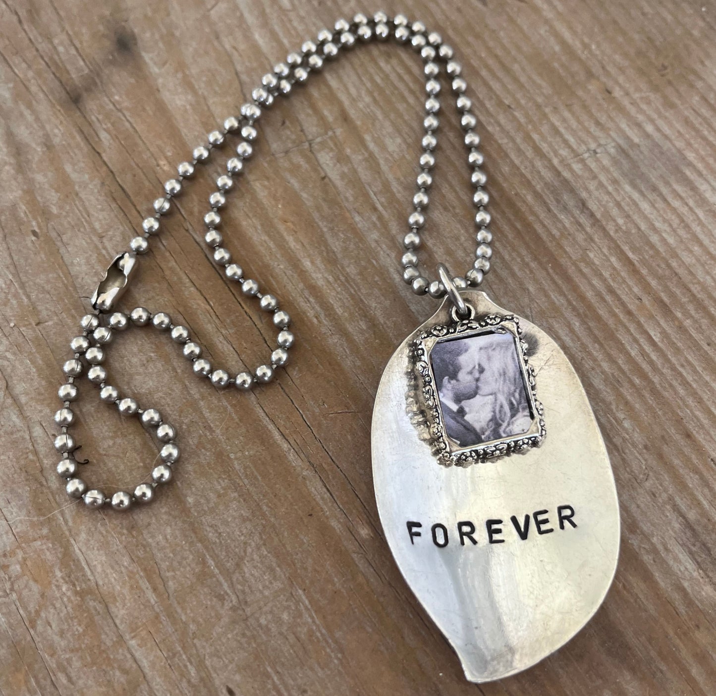 Close-up detail of FOREVER hand-stamped spoon pendant with pewter frame for photo, reclaimed vintage silverware, 2.375 inches long