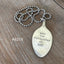 Close-up of hand-stamped spoon pendant with 'Tame the Savageness of Man' quote showing reclaimed vintage silverware, one-of-a-kind compassion-themed design