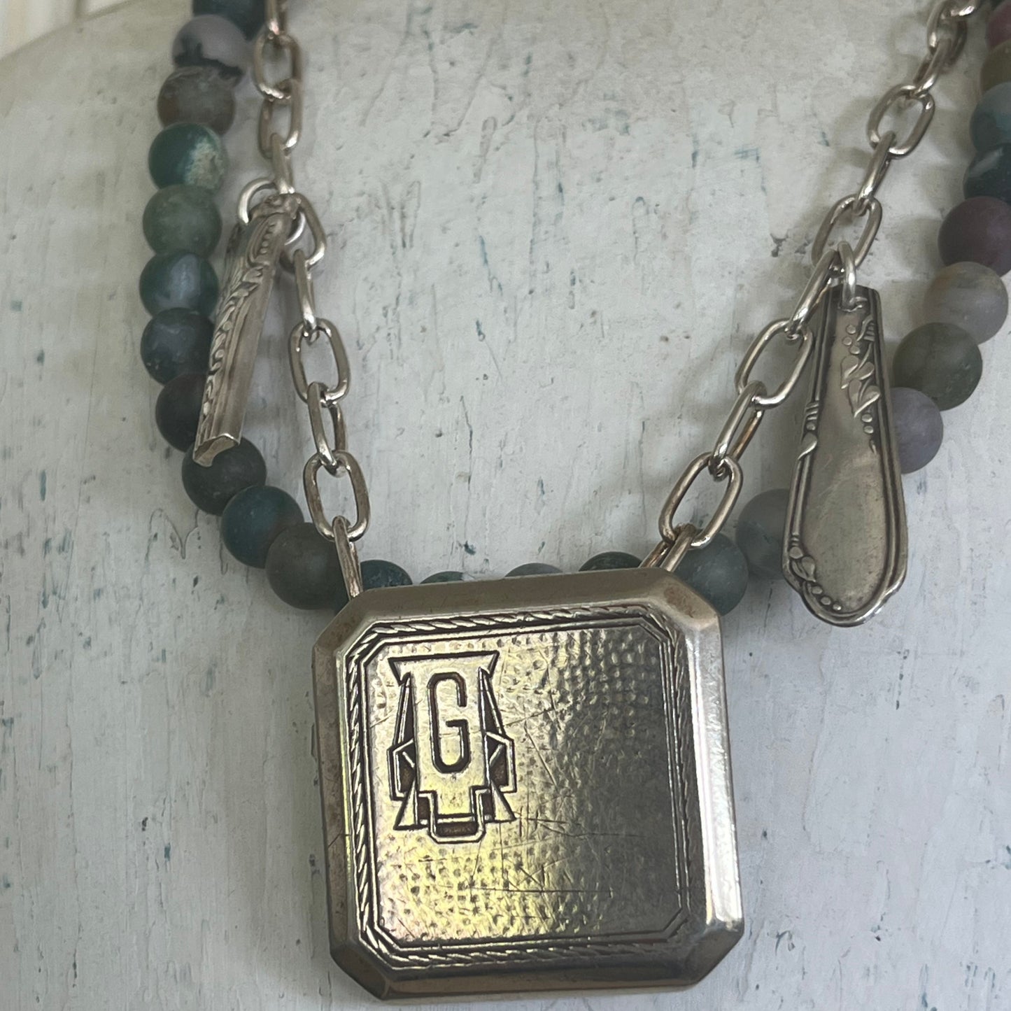 Close-up detail of vintage 1920s monogram G belt buckle pendant with upcycled silverware pieces - handcrafted artisan necklace