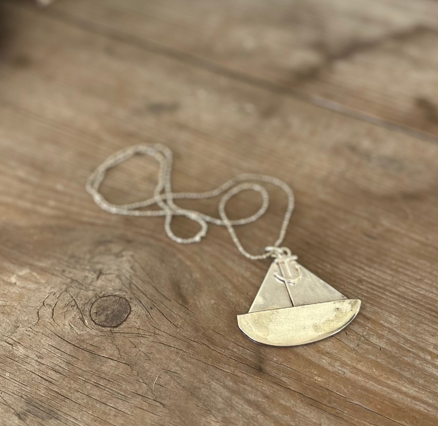 Close-up of vintage spoon sailboat pendant showing hand-stamped detail and anchor charm, sustainable artisan nautical jewelry