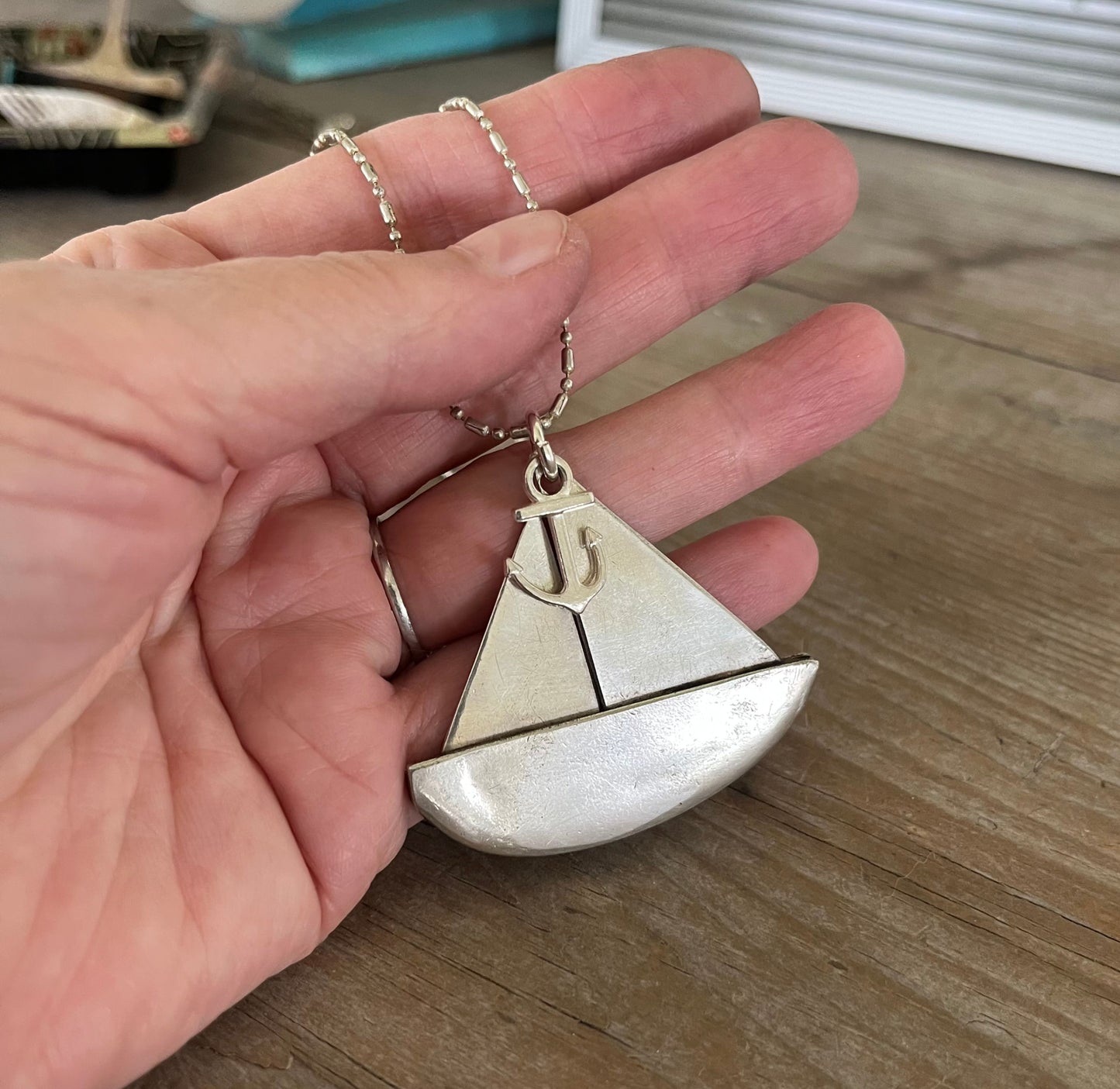 dpoon sailboat pendant held in hand showing scale at ~2 inches wide, handmade upcycled vintage silverware nautical necklace