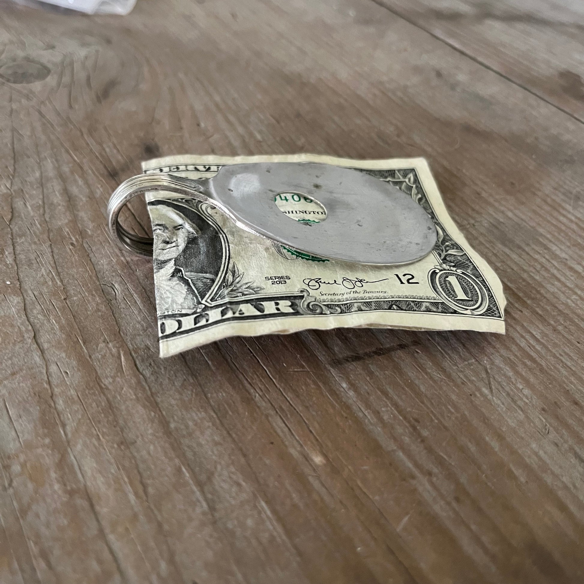 Side view of guitar money clip showing upcycled vintage silverware spoon with bent neck and clip mechanism