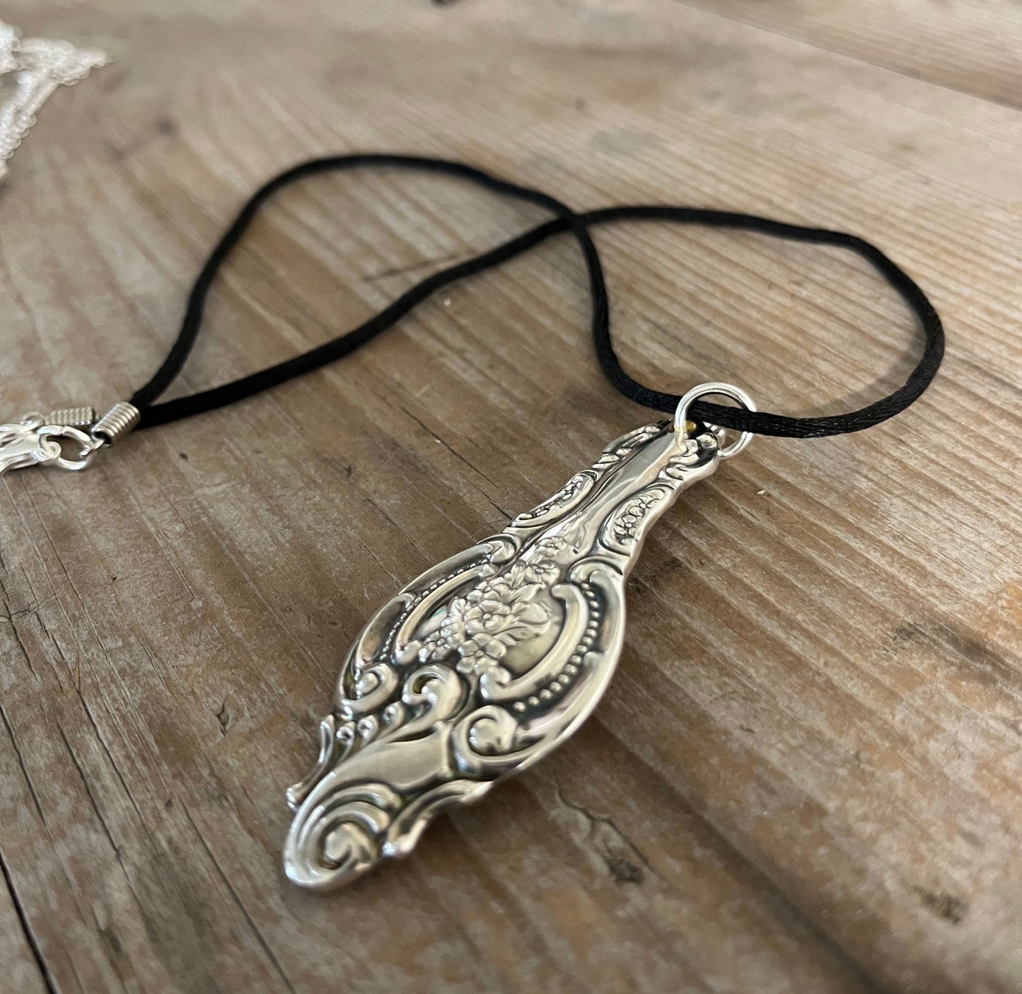 Close-up of Wallace Baroque silverplate ladle pendant showing deep ornate pattern detail, handcrafted vintage silverware necklace