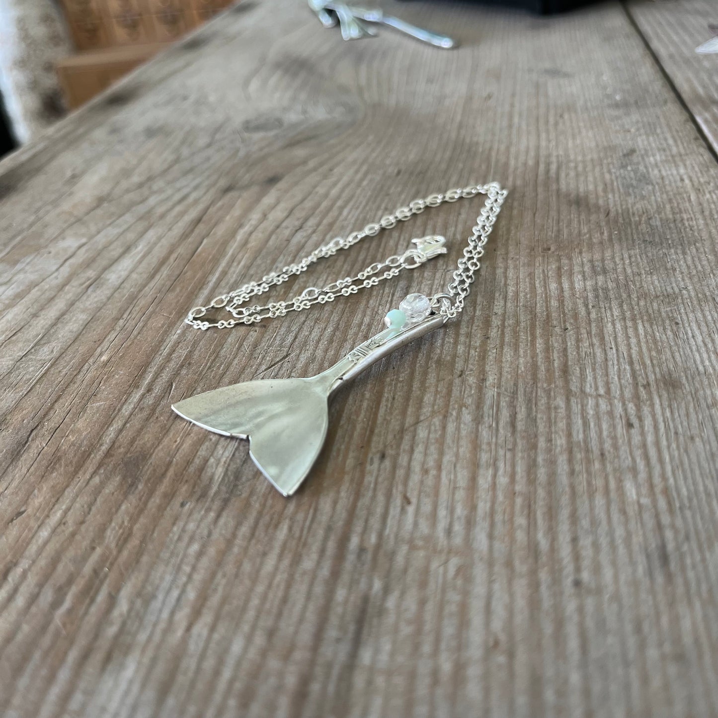 ide view of upcycled spoon mermaid tail necklace showing hand-shaped contoured pendant, artisan ocean jewelry