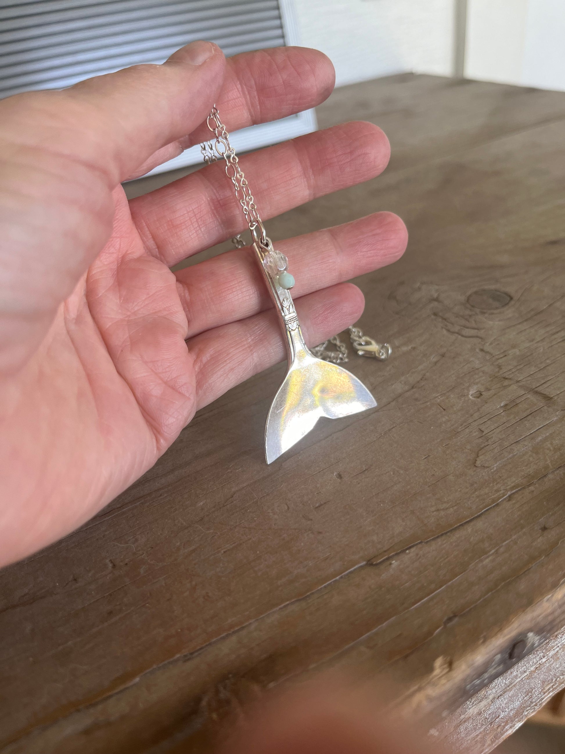 Detail of handcrafted mermaid tail pendant made from vintage silverplate teaspoon, sustainable beach-inspired jewelry