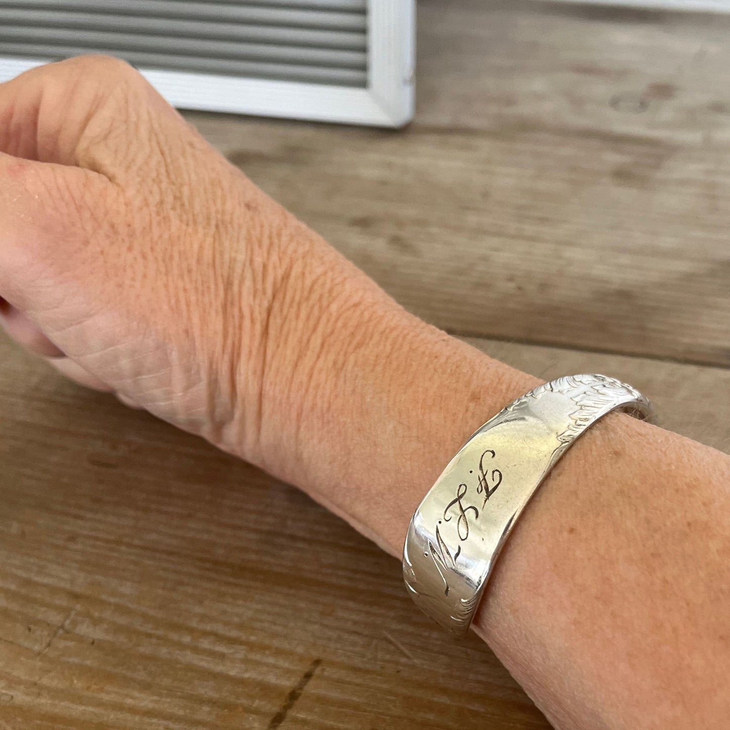 FLW monogram spoon cuff bracelet worn on wrist - handcrafted from upcycled vintage silverware - Laughing Frog Studio
