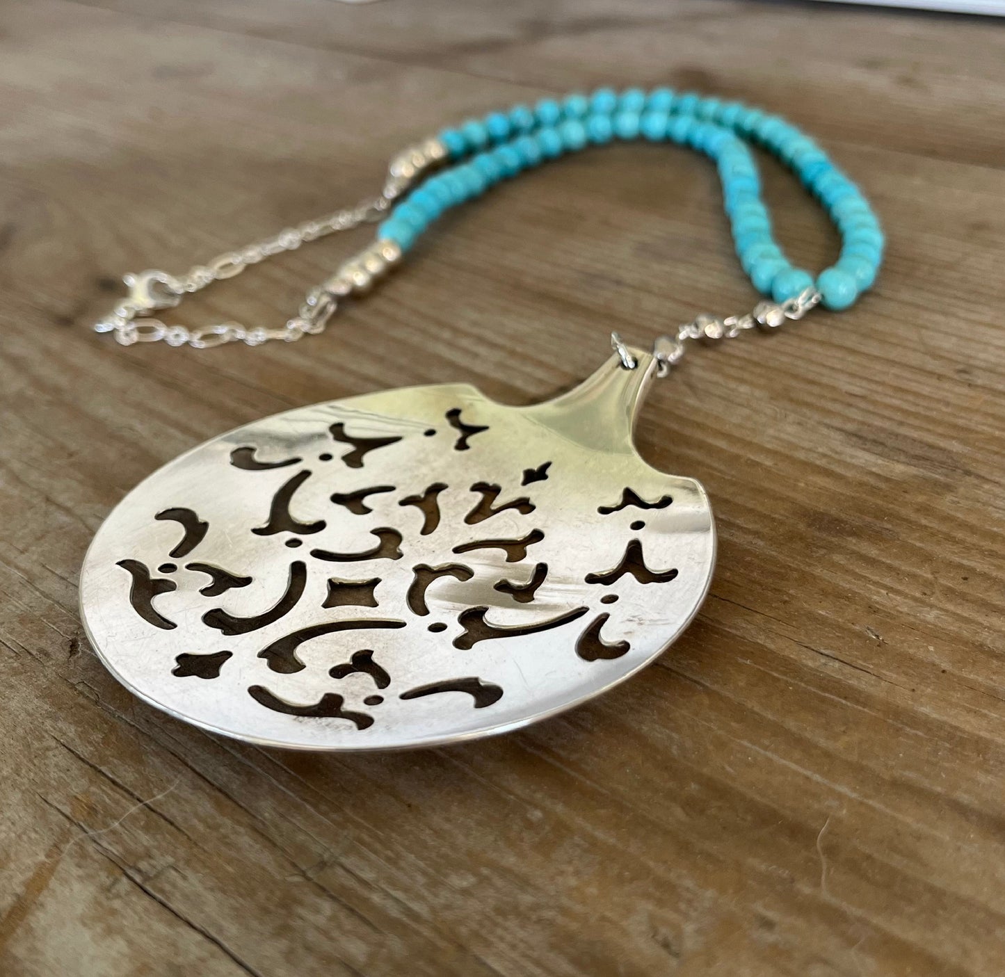 Close-up detail of handcrafted vintage tomato server pendant with turquoise magnesite beads - eco-friendly upcycled silverware jewelry
