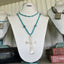 Vintage spoon bowl transformed into artisan cross pendant on 31-inch turquoise glass and Nepali bead necklace shown on a necklace display bust