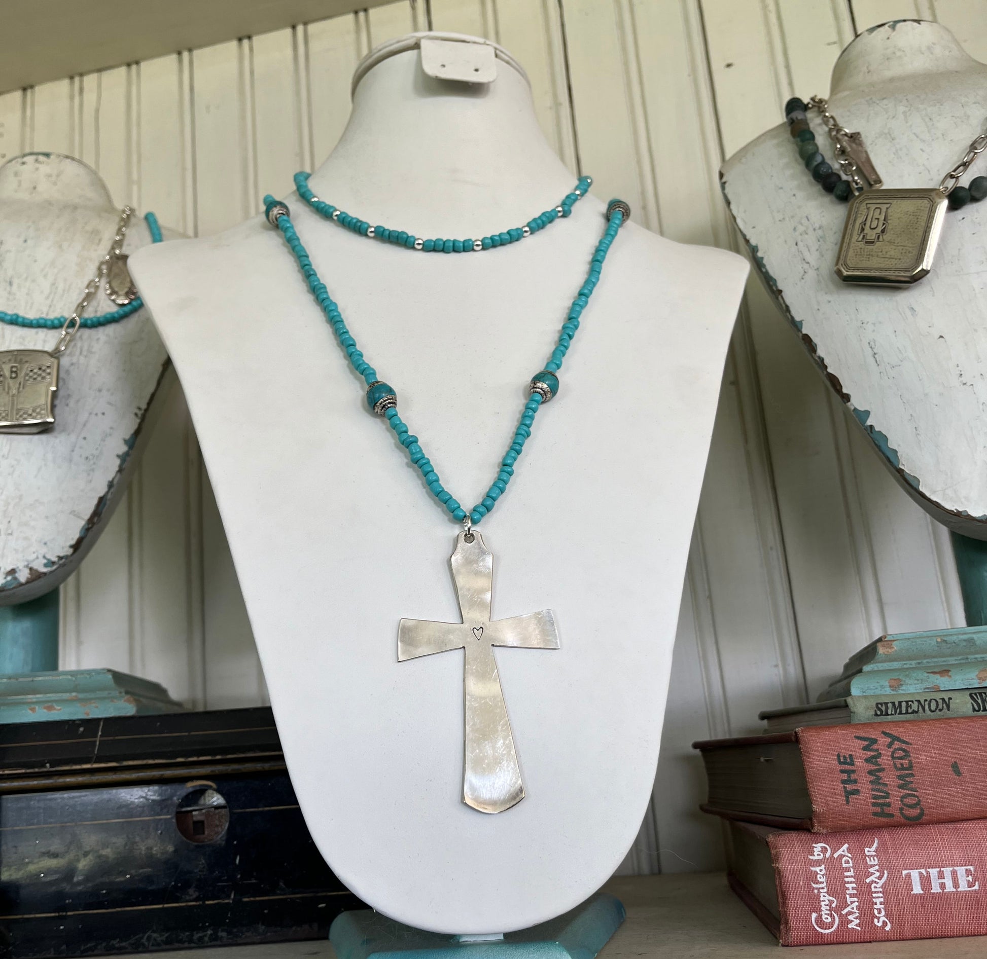 Vintage spoon bowl transformed into artisan cross pendant on 31-inch turquoise glass and Nepali bead necklace shown on a necklace display bust