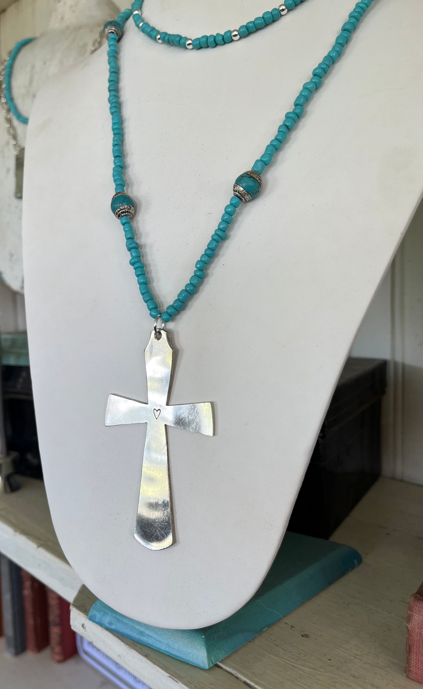 Side view of Artisan spoon cross necklace with turquoise beads and decorative Nepali beads