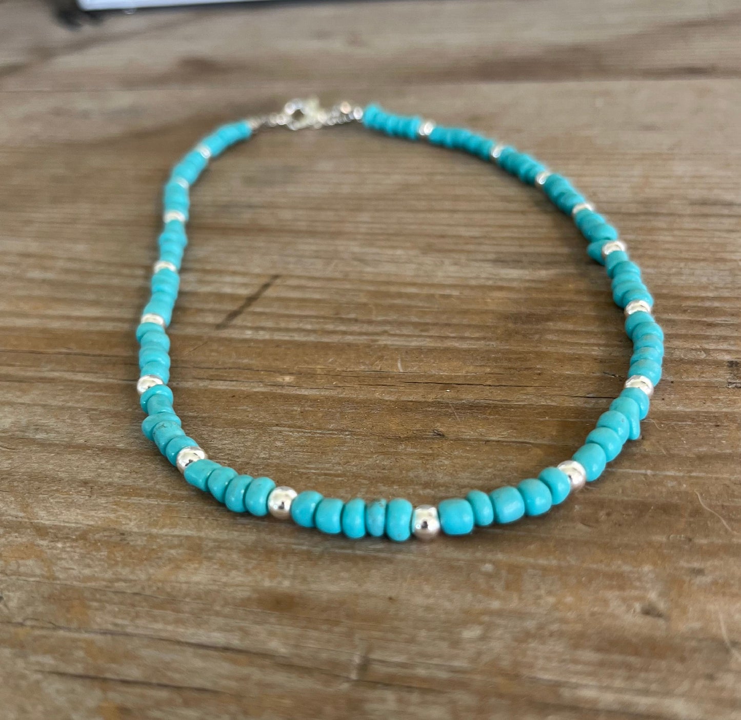 Close-up of turquoise colored glass bead choker showing silverplate accent beads, handmade layering necklace