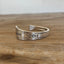 BADASS stamped spoon cuff bracelet flat lay showing Friendship/Medality pattern detail - handcrafted from upcycled vintage silverware