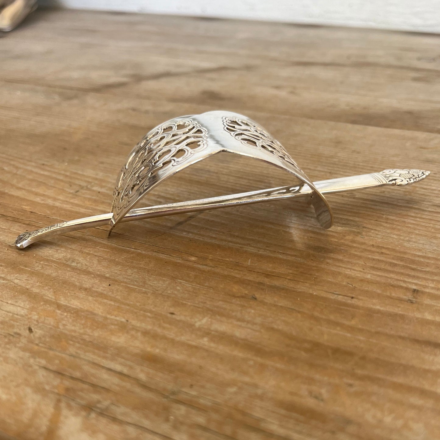 Side view of vintage cake server hair barrette showing curved silverplate shape