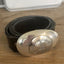 Close-up of PEACE belt buckle showing hand-stamped peace symbol on round bullion spoon applied to casserole spoon, one-of-a-kind silverplate