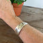 vintage BADASS hand-stamped Community White Orchid silverplate spoon cuff bracelet worn on model wrist - hand-stamped spoon cuff bracelet - handcrafted from upcycled vintage silverware - Laughing Frog Studio