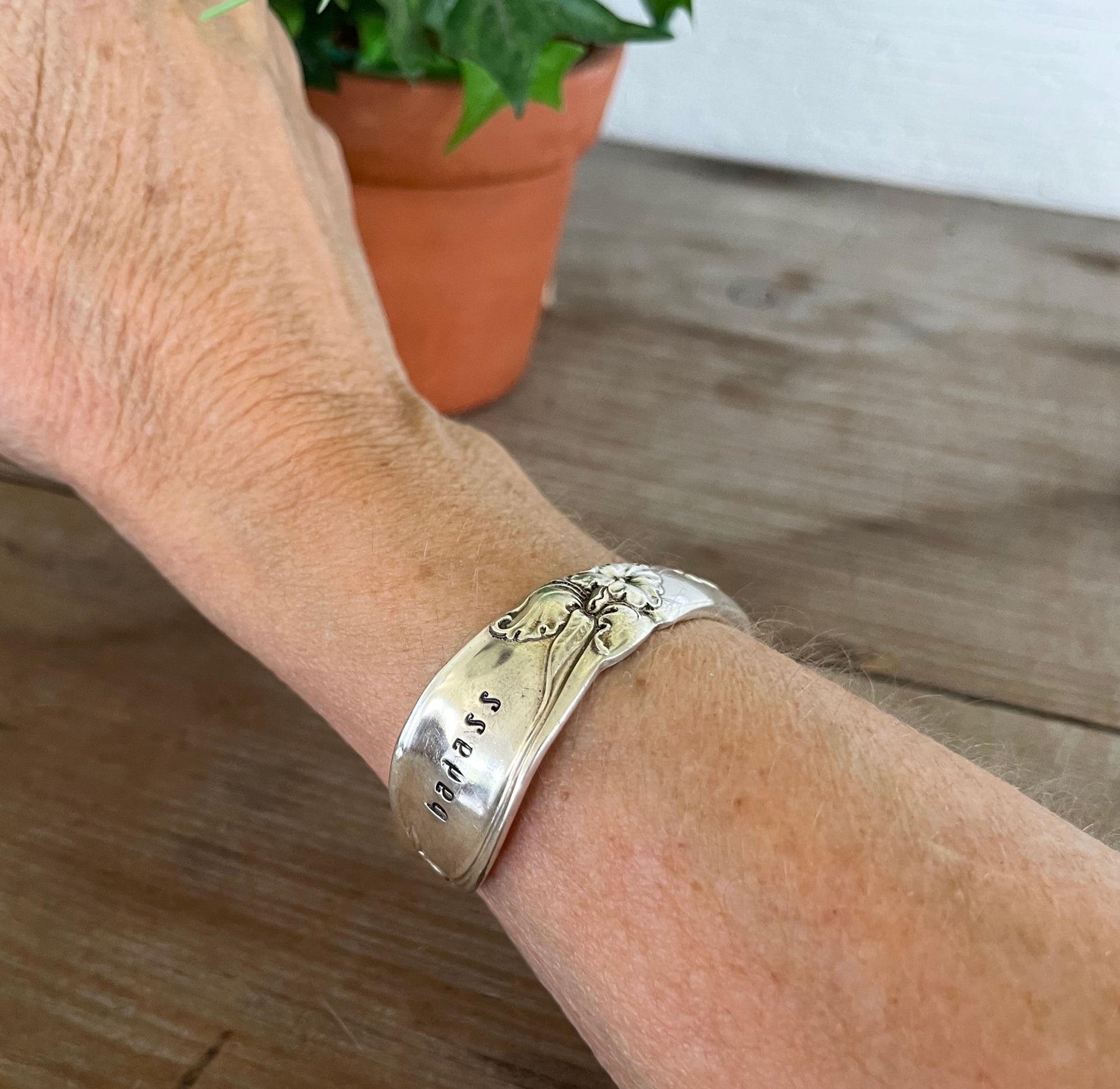 vintage BADASS hand-stamped Community White Orchid silverplate spoon cuff bracelet worn on model wrist - hand-stamped spoon cuff bracelet - handcrafted from upcycled vintage silverware - Laughing Frog Studio